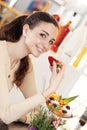 Beautiful young smiling woman with cup of fruit salad with ice cream on top at the cafe coffee bar, ice cream shop and pastry shop Royalty Free Stock Photo