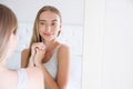 Beautiful young smiling woman,girl is touching her face while looking at the mirror. Royalty Free Stock Photo