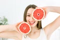 Beautiful young smiling woman with long hair, flawless skin , holding grapefruit pieces isolated on white. Funny playful Royalty Free Stock Photo