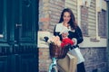 Smiling woman reading the notice on smart phone and walking down the street with her bicycle