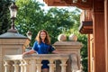 Beautiful young smiling woman walking in city park near famous old architecture building at summer day wearing dress and looking Royalty Free Stock Photo