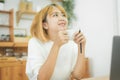 Beautiful young smiling woman working on laptop while enjoying drinking warm coffee sitting in a living room at home. Royalty Free Stock Photo