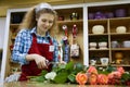 Beautiful young smilling woman florist are cutting the roses in flower shop Royalty Free Stock Photo