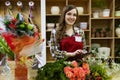 Beautiful young smilling woman florist are using a tablet in flower shop