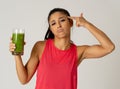 Beautiful young sport woman tired of diet holding green smoothie in dislike