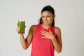 Beautiful young sport woman tired of diet holding green smoothie in dislike