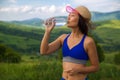 Beautiful young sports asian woman drinking water a refresh after torrid heat summer day in mountains.