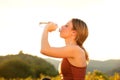 Beautiful young sports woman drinking water outside