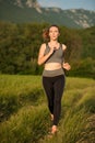 Beautiful young sporty woman workout in nature runs on a path on meadow