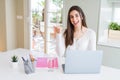 Beautiful young student woman studying for university using laptop and notebook pointing and showing with thumb up to the side Royalty Free Stock Photo