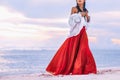 Beautiful young stylish boho woman walking on the beach at sunset Royalty Free Stock Photo