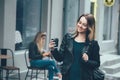 Beautiful young stylish casual woman wear in fashion clothes and staying on street and holding black cup Royalty Free Stock Photo