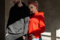 Beautiful young stylish couple in trendy hoodie indoors with sunshine. Hipster girl in red hoodie and handsome man with beard Royalty Free Stock Photo