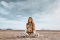 Beautiful young stylish pregnant woman with boho accessories on the beach at sunset