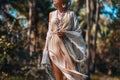 Beautiful young stylish woamn in boho dress walking on a field at sunset