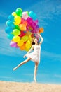 Beautiful young stylish woman with ainbow balloons in hands against sky. Positive girl on nature. Smiling woman outdoors Royalty Free Stock Photo