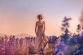 Beautiful young stylish woman posing on the field at sunset