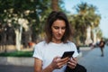 Beautiful young stylish woman walking  streets using modern smartpone, hipster female blogger typing text message on her cellphone Royalty Free Stock Photo