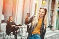 Beautiful young stylish woman wear in fashion clothes and staying in front of cafe and holding black cup of coffee, Royalty Free Stock Photo