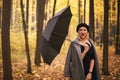 Beautiful young stylish woman with black umbrella while walking in autumn forest on rainy day Royalty Free Stock Photo