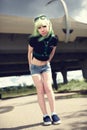 Beautiful young swag woman with green hair posing near highway road