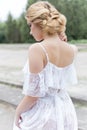 Beautiful young sweet blonde girl with wedding bouquet in the hands of the boudoir in a white dress with evening hairstyle walks