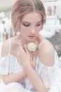 Beautiful young sweet blonde girl with wedding bouquet in the hands of the boudoir in a white dress with evening hairstyle walks