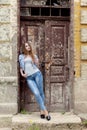 Beautiful young sweet girl with red hair in jeans standing near the door of the old city Royalty Free Stock Photo