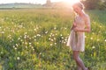 Beautiful young sweet girl in a white dress with hair on the head oblique walks in a field at sunset Royalty Free Stock Photo