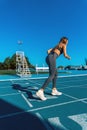 Beautiful young tanned woman with long dark hair, prepared to do a sprint running with her legs bent and in position on a blue Royalty Free Stock Photo