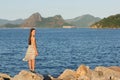 Beautiful young teen girl smiling, standing on stones near sea i Royalty Free Stock Photo