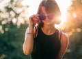 Beautiful young teenage girl in fancy sunglasses dressed in black dress challenging smiling at the camera with a warm sunset Royalty Free Stock Photo