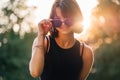 Beautiful young teenage girl in fancy sunglasses dressed in black dress challenging smiling at the camera with a warm sunset Royalty Free Stock Photo