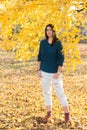 Beautiful young teenage girl posing under tree with yellow leafs in the park at autumn Royalty Free Stock Photo