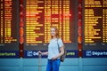 Beautiful young tourist girl with backpack and carry on luggage in international airport Royalty Free Stock Photo