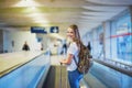 Beautiful young tourist girl with backpack and carry on luggage in international airport Royalty Free Stock Photo
