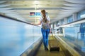 Beautiful young tourist girl with backpack and carry on luggage in international airport Royalty Free Stock Photo