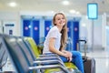 Beautiful young tourist girl with backpack and carry on luggage in international airport Royalty Free Stock Photo