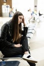 Beautiful young tourist girl with backpack and carry on luggage in international airport, waiting for her flight, looking upset. Royalty Free Stock Photo