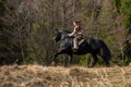Beautiful young viking warrior woman with sword riding big black horse in the mountains scouting the land Royalty Free Stock Photo