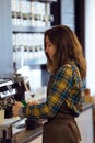 Beautiful young waitress making coffee using a professional machine in a coffee shop.