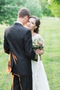 Beautiful young wedding couple in a green garden, broom`s back hugged by a nice bride Royalty Free Stock Photo