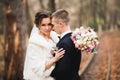 Beautiful young wedding couple posing with bouquet of flowers in hands