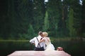 Beautiful young wedding couple sitting on the pier.