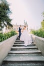 Beautiful young wedding couple on stairs in park. Romantic antique palace at background