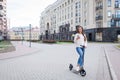 Beautiful, young, and white-toothed girl with long brown hair stopped while riding the scooter, to write to a friend on the phone.