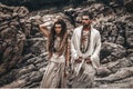 Beautiful young wild free couple in tribal costumes at the stone background