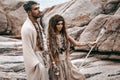 Beautiful young wild free couple in tribal costumes at the stone background