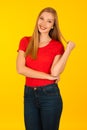 Beautiful young woma in red t shirt and jeans over yellow background