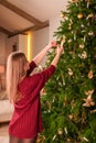 A beautiful young woman adorns a Christmas tree at home. Royalty Free Stock Photo